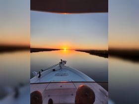 A serene sunset view from the bow of a boat, showcasing tranquil waters and a picturesque horizon — perfect for peaceful evening cruises.