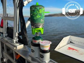 A portable cooking setup featuring a propane stove and food container, perfect for onboard meals while enjoying a day on the water.