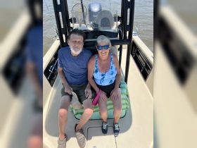 A happy couple enjoys a day on the water, sitting together on a fishing boat, capturing the joy of their boating experience.