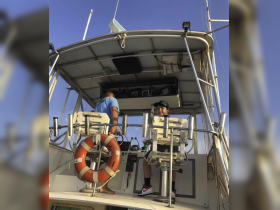 A young boy and an adult enjoy time at the helm of a boat, showcasing the interior space and seating arrangements, perfect for family outings on the water.