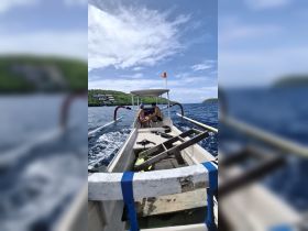 A couple enjoys a moment aboard a boat, with snorkeling gear visible, set against a beautiful coastal backdrop — perfect for adventure seekers exploring the waters.