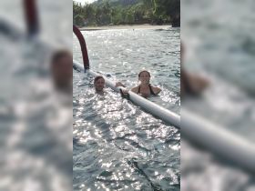 A couple enjoys a refreshing swim in the ocean, showcasing the fun and adventure of water activities during their trip.