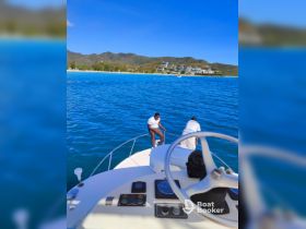Two individuals are seen on the bow of a boat, enjoying the beautiful turquoise waters and scenic backdrop, perfect for a day of adventure on the water.