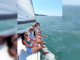 A group of friends enjoys a sunny day sailing, with smiles and laughter as they dip their feet in the water — the perfect summer adventure on the waves.