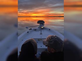 A couple enjoys a breathtaking sunset view from their boat, creating a perfect romantic atmosphere on the water.