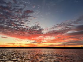 A breathtaking sunset paints the sky in vibrant hues over calm waters, creating a perfect backdrop for evening boat trips and serene moments on the water.