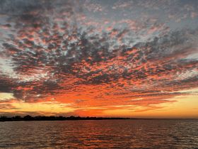 A breathtaking sunset paints the sky in vibrant hues over the water, creating a picturesque backdrop perfect for evening boat cruises.