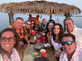 A lively group of friends celebrates together on a boat, adorned with leis and enjoying drinks — perfect for memorable gatherings and parties on the water.