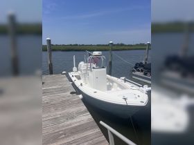A pristine speedboat docked at the pier, showcasing its sleek design against a serene water backdrop — perfect for fishing or leisurely cruises.