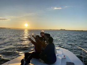 A group of friends celebrates with cocktails on the deck of a boat at sunset, creating the perfect backdrop for memorable moments on the water.