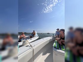 A lively group enjoys a sunny day on the water, relaxing on a boat with friends — perfect for a fun day out on the sea.
