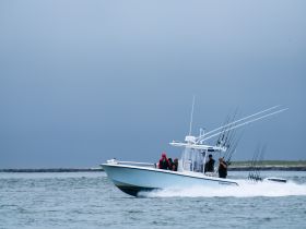 A group of anglers aboard a fishing boat navigate the waters, showcasing the thrill of on-water fishing adventures.
