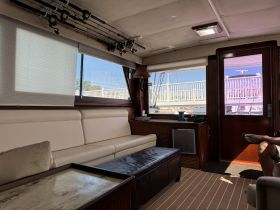 Interior view of a comfortable cabin on a boat, featuring plush seating and fishing rods, perfect for relaxing or preparing for a day on the water.