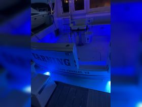 A well-lit interior view of a boat's helm area, showcasing seating and ambient blue lighting, perfect for evening outings.