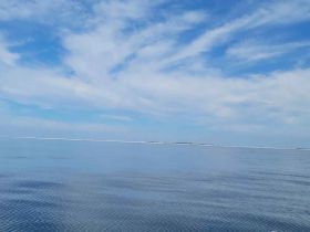 A serene view of calm waters and a clear sky, but the image lacks identifiable subjects or details.