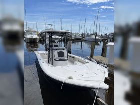 A sleek speedboat docked at the marina, showcasing its modern design against a backdrop of masts and clear blue skies.