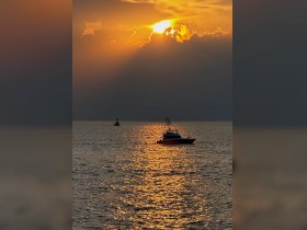 A serene sunset view featuring a boat silhouetted against the shimmering waters, creating a picturesque scene perfect for evening cruises.