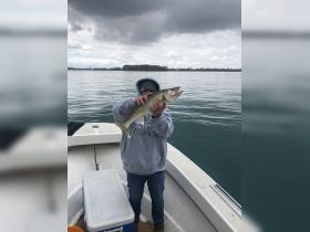 A proud angler holds up a freshly caught walleye aboard a boat, showcasing the thrill of fishing on the water.