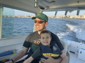 A joyful moment on the water as a father and son enjoy a boat ride together, capturing the essence of family fun and adventure.