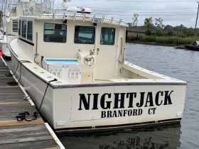 A clear view of the 'NIGHTJACK' boat docked at the marina, showcasing its structure and name — perfect for fishing charters or private excursions.