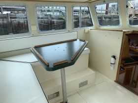 Interior view of a boat cabin featuring a seating area and table, perfect for relaxing or dining while on the water.