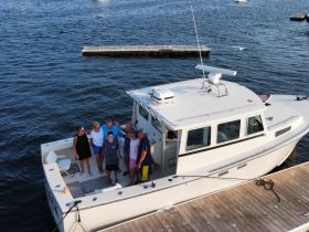 A cheerful group poses on the deck of a boat, capturing a memorable moment together — perfect for family gatherings or celebrations on the water.
