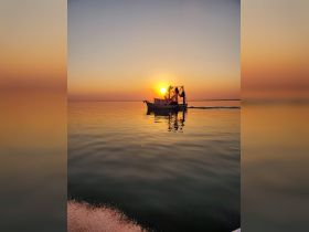 A picturesque fishing boat glides across calm waters at sunset, creating a serene scene perfect for maritime photography.