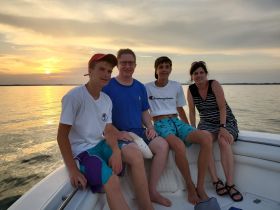 A family enjoys a beautiful sunset on a boat, capturing a memorable moment together on the water.