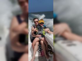 A joyful moment captured of a mother and daughter enjoying a boat ride, both wearing life jackets, showcasing the fun and safety of family outings on the water.