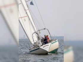 A couple enjoys a sailing experience aboard the 'Seeker,' navigating the waters with a sense of adventure.