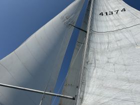 Close-up view of the sails of a sailboat against a clear blue sky, showcasing the vessel's structure and design.