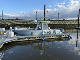 A sleek boat named 'Olivia Rose' docked at the marina, showcasing its design against a serene water backdrop.