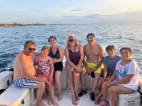 A cheerful family enjoys a boat ride together, capturing a moment of joy against a beautiful sunset backdrop — perfect for family outings on the water.