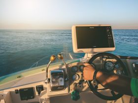 A close-up view of the helm and console of a boat, showcasing the steering wheel and navigation equipment, perfect for those looking to explore the open waters.