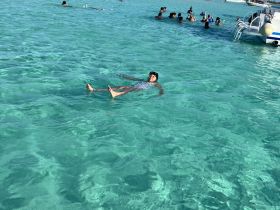 A joyful scene of a child floating in crystal-clear waters, surrounded by a group enjoying a fun day of swimming and snorkeling — a perfect tropical getaway.