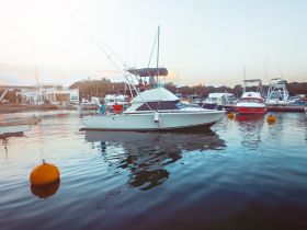 A beautiful yacht docked at a marina, surrounded by other boats, showcasing a serene evening atmosphere.