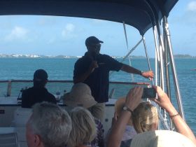 A tour guide engages guests aboard a boat, providing insights while cruising through beautiful waters — a perfect moment for group experiences on the ocean.