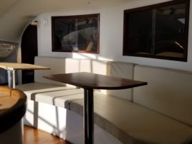 A cozy interior view of a boat cabin featuring comfortable seating and tables, perfect for relaxing during a day on the water.