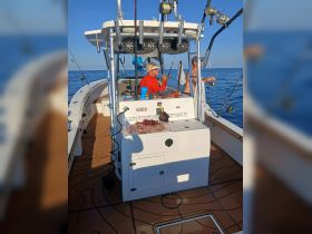 Two fishermen enjoy a day on the ocean, actively fishing from their boat. The vibrant atmosphere captures the excitement of a fishing adventure.