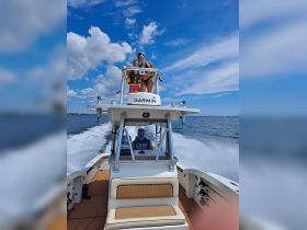 A joyful moment on the water as a woman and a child enjoy the breeze from the top of a boat, while a man steers from the helm — perfect for family outings and summer adventures.