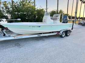 A pristine boat is showcased on a trailer, ready for adventure. The sleek design and vibrant color make it an ideal choice for fishing or leisure outings.