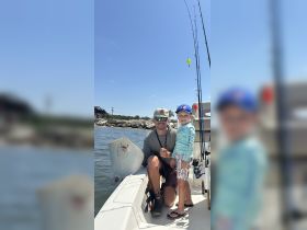 A joyful moment captured with a child and an adult posing with a stingray on a fishing boat, showcasing a memorable wildlife encounter on the water.