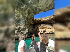 A group of friends enjoys a scenic boat ride, exploring a stunning cave with crystal-clear waters — a perfect adventure for nature lovers.