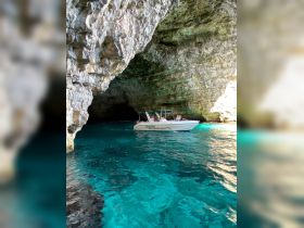 A boat navigates through a stunning cave with crystal-clear turquoise waters, showcasing the beauty of nature and adventure on the water.