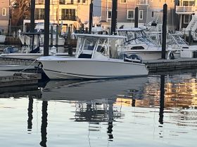 A sleek speedboat docked at the marina, reflecting the warm colors of the surrounding buildings in the calm water — perfect for a day on the water.