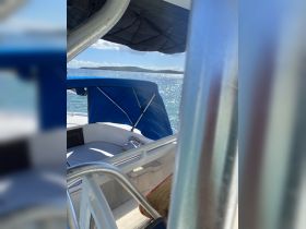 A cozy interior view of a boat featuring comfortable seating and a blue canopy, perfect for relaxing while enjoying the scenic waters.