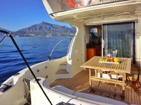 A cozy dining area inside a boat featuring a wooden table adorned with fresh fruits, perfect for enjoying meals while cruising on calm waters.