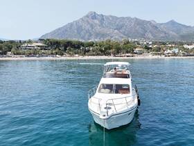 A stunning yacht glides through crystal-clear waters with a picturesque mountain backdrop, perfect for luxury boating experiences.
