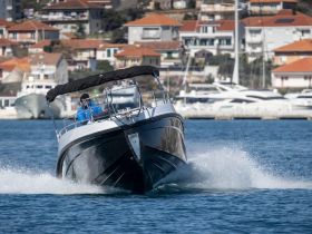 A speedboat navigates through the water with a driver at the helm, showcasing the thrill of boating adventures against a scenic backdrop.