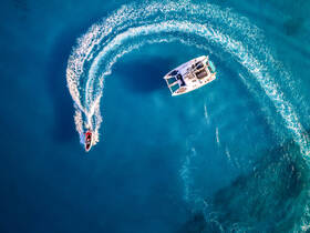 An aerial view captures two boats navigating through vibrant turquoise waters, showcasing the excitement of on-water activities.